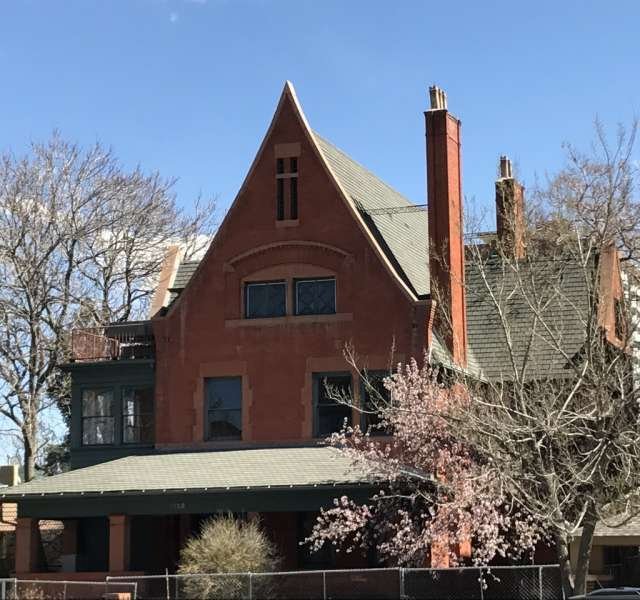 a house with trees in front of a brick building